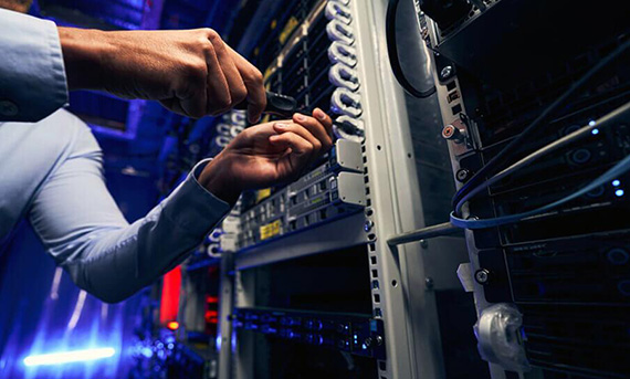 Una persona interviene su un rack di server in un ambiente di data center poco illuminato.